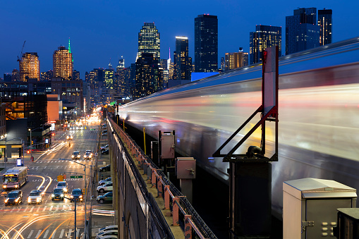 Motion blurred subway train against New York skyline at dusk, Queens, New York City.