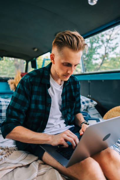 istock Young caucasian man work on computer sitting in a van, freelancer using laptop during traveling 1332746764