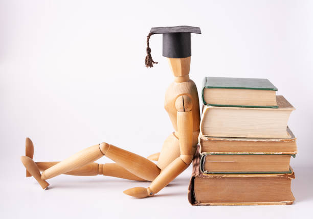 el estudiante de madera se sienta de espaldas contra una pila de libros. - mannequin book education doll fotografías e imágenes de stock