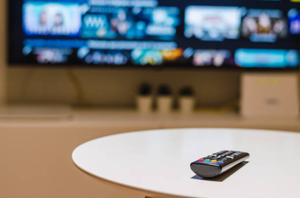 Remote control, smart tv and living room An adult man enjoying his Saturday night alone, watching TV in his living room remote control on table stock pictures, royalty-free photos & images