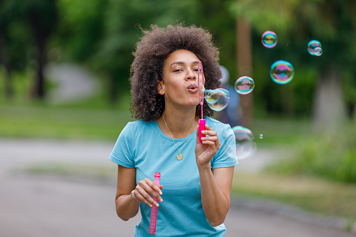 Happy African-American Woman is Spending Wonderful Time and Having a Lot of Fun in Nature While Blowing Bubbles.