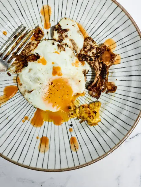 Above view of plated cooked over easy egg with drizzled soy sauce