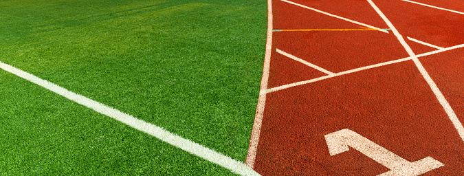green artificial football field and red brown running tract sport filed banner background