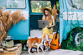 Young caucasian woman using laptop computer while sitting o a van outdoors.