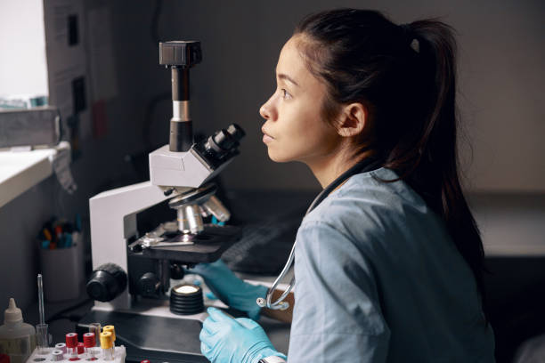 istock Thoughtful Asian lab assistant sits near microscope looking out of window at workplace 1332755072