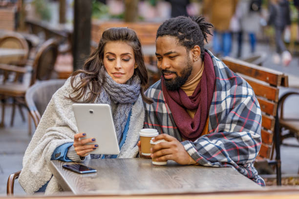 istock A Young Multi-Ethnic Couple is Spending a Wonderful Evening Together, Having a Lovely Communication and Sharing a Fresh Drink, and Using a Digital Tablet. 1332757610
