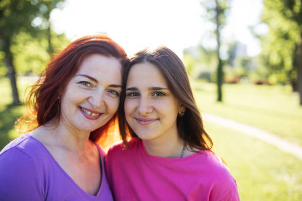mother and teenager daughter at the park, close up portrait