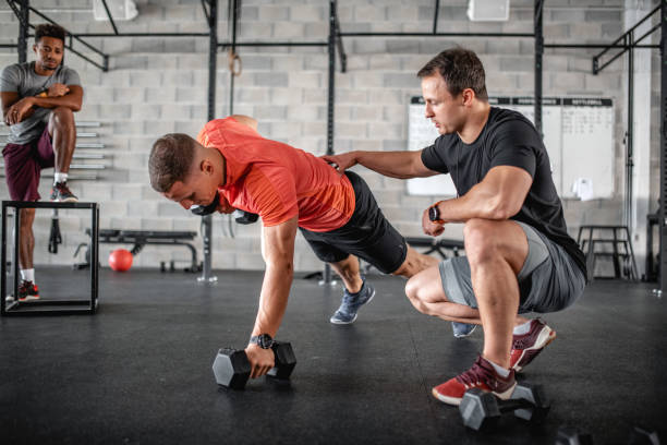 istock Coach Supervising Athlete as He Does Renegade Row Push-Ups 1332764004