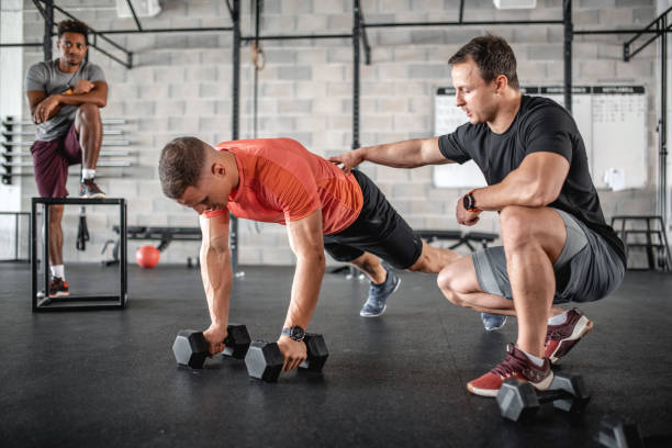 istock Coach Supervising Athlete as He Does Renegade Row Push-Ups 1332764005
