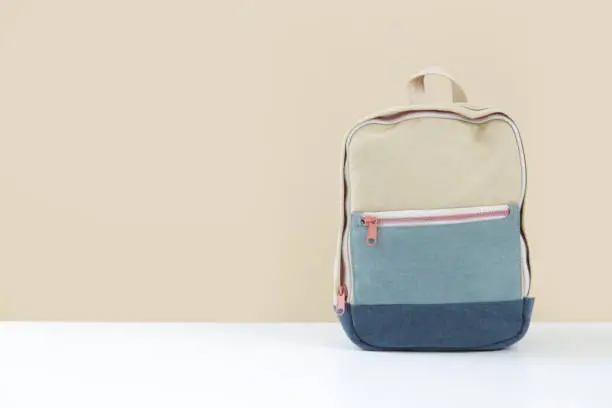 Photo of Canvas backpack on the table against beige wall with copy space