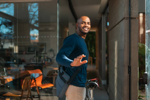 jeune homme arrivant à vélo sur le lieu de travail - cycling bicycle healthy lifestyle green photos et images de collection