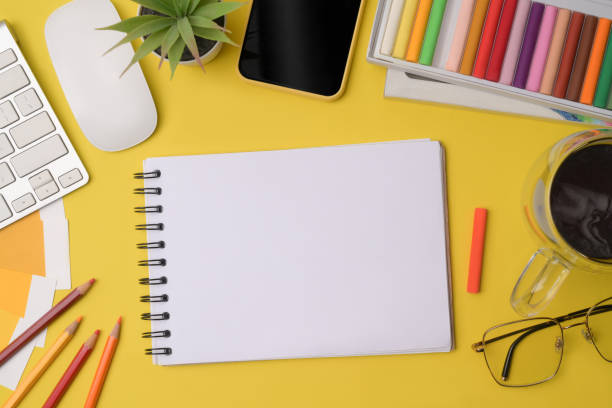 istock Empty notebook, mobile phone coffee cup and colored crayons on yellow background. 1332795182