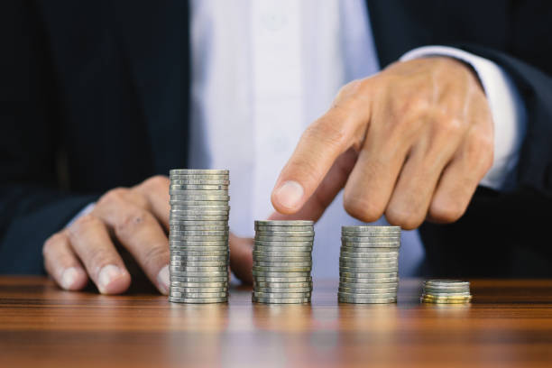 istock Businessman touch on coins stack on wooden table , Man stacking coins  for saving money retirement ,Men coins stack for investment 1332802569