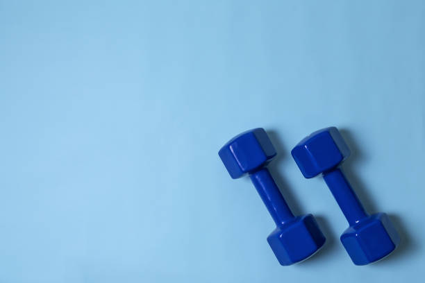 istock Blue dumbbells on light blue background with copy space, flat lay 1332803320