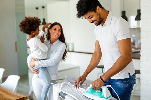 Happy young handsome african american man ironing clothes at home. Family happy love concept