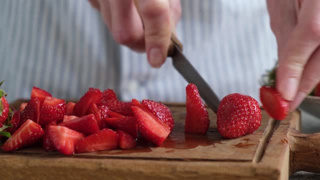 Female hands cutting strawberries