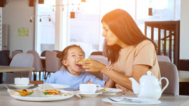 istock Lady mom holds pizza slice and daughter eats in cafe 1332808851