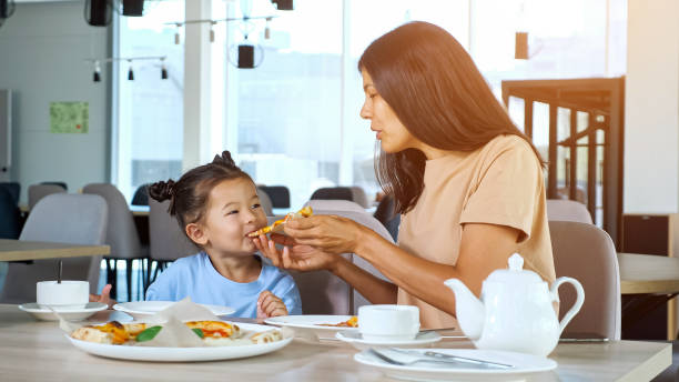istock Lady mom holds pizza slice and daughter eats in cafe 1332808861