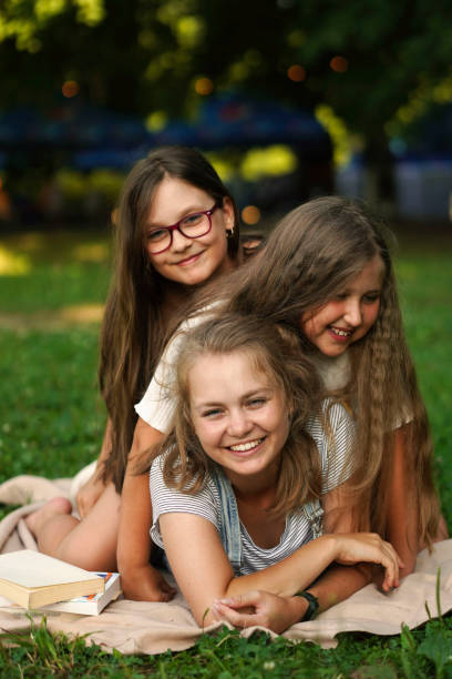 tres hermanas sonrientes divirtiéndose al aire libre. hermanas juntas para siempre. concepto de familia feliz. - child laughing blond hair three people fotografías e imágenes de stock