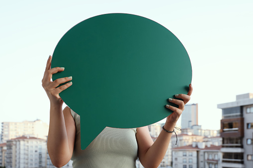 Woman hiding face behind speech bubble