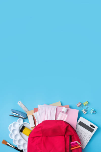istock Pink backpack with stationery over blue table background. 1332818484