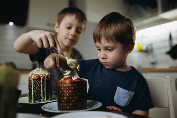 frères décorant des gâteaux de pâques avec glaçage à glace et garniture au sucre. image avec mise au point sélective - little cakes photos et images de collection