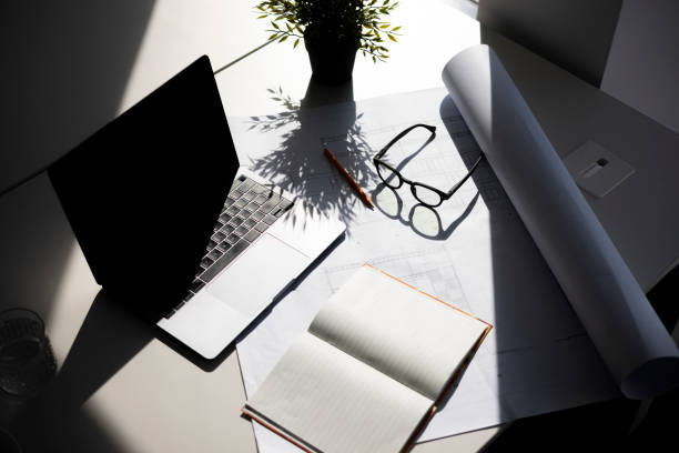 High angle view of a workplace Desk with a laptop in office, a notebook and architectural blueprint on the table