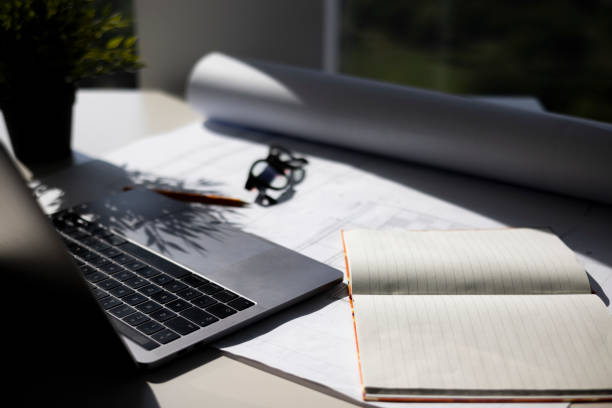 istock Workplace Desk with a laptop in office, a notebook and architectural blueprint on the table 1332824752