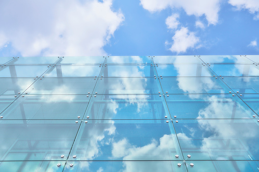 Building in steel and glass reflecting sky and clouds as a mirror. Copy space in anonymous industrial design building
