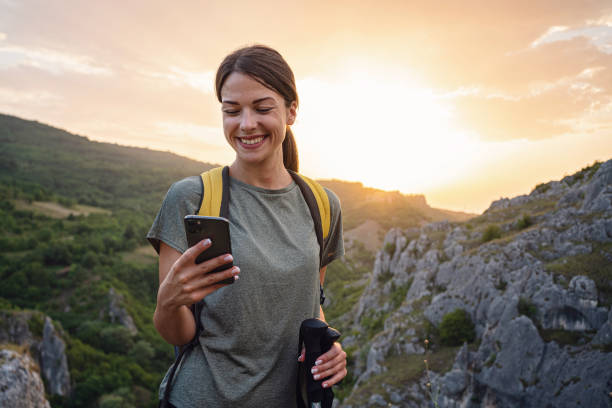 GPS mobile app, just said that i arrived at the top of the mountain Solo female hiker, using her mobile phone during her hike, to send some text messages or to see her location on GPS app, while enjoying her solo mountain adventure life balance photos stock pictures, royalty-free photos & images