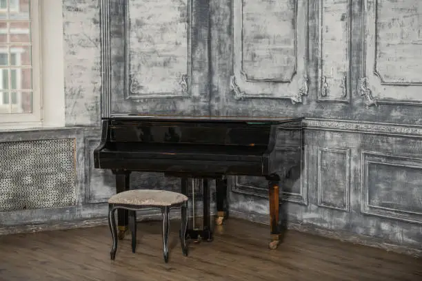 An old retro grand piano stands in the room. Vintage room.
