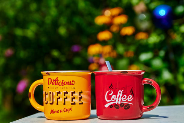 istock A red and a yellow coffee cup with blurred flowers in the background. 1332838033