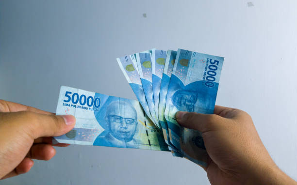 istock asian man hand holding and picking 50000 rupiah with total 300000 rupiah note bills 1332840353