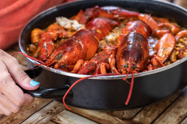 femme prenant de la paella espagnole avec du homard. gros plan - food rice lobster scampi photos et images de collection