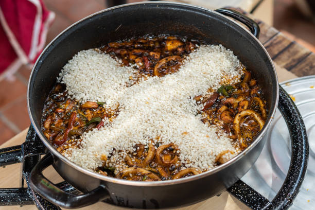 ajouter du riz dans un pot pour faire une paella espagnole - food rice lobster scampi photos et images de collection