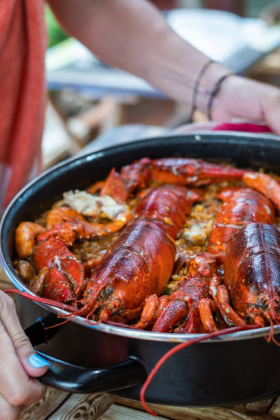 donna che prende la paella spagnola con l'aragosta. primo tempo - seafood lobster paella prepared shellfish foto e immagini stock