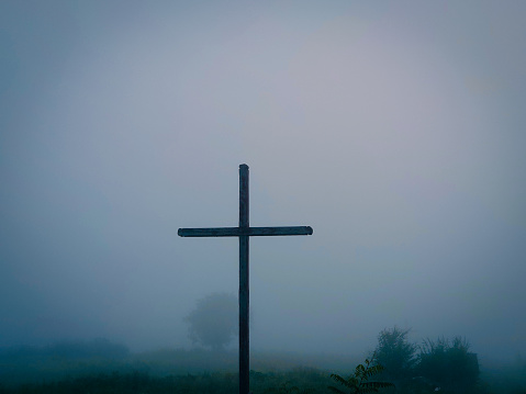large wooden cross in the morning fog. Symbol of the Christian faith.