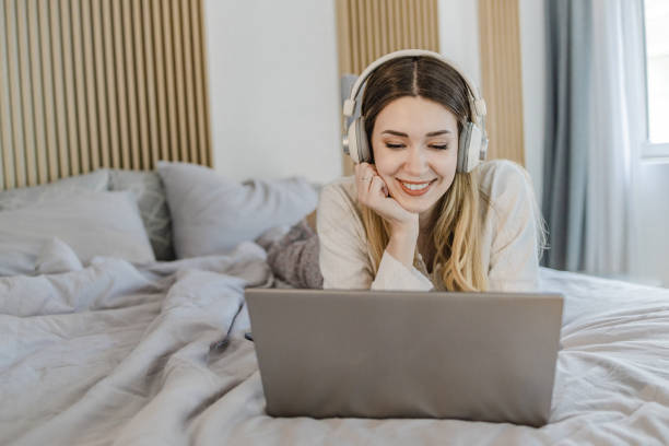 istock Young woman uses a laptop in bed 1332847190