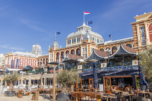 Scheveningen, the Netherlands - Apr 26, 2021: The Kurhaus of Scheveningen with restaurants around on the boulevard on a sunny day