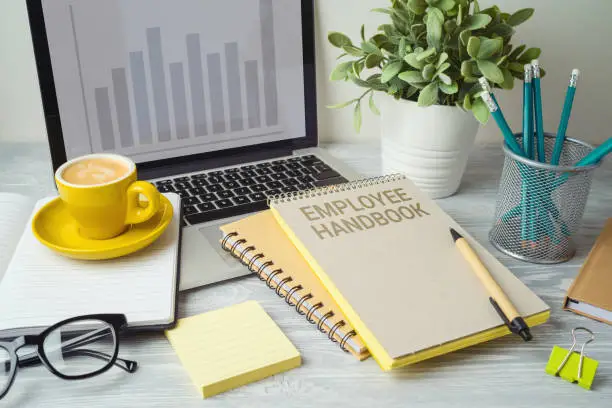 Photo of Employee handbook on office table with computer laptop. Business concept for design