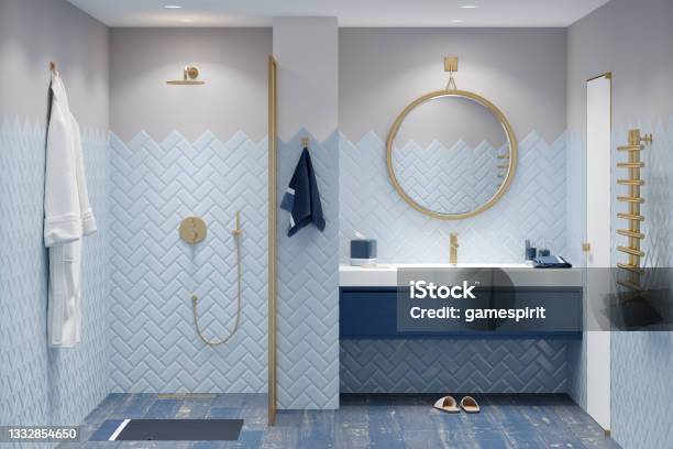 A Modern Bathroom In Blue Tones With Gold Fittings A Bathrobe Next To The Shower A Round Mirror Over A Large Washbasin With A Blue Cabinet A Golden Heated Towel Rail Next To A White Door Stock Photo - Download Image Now