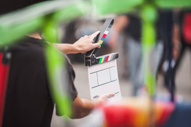 uomo che tiene un clapperboard davanti alla telecamera - assicella foto e immagini stock