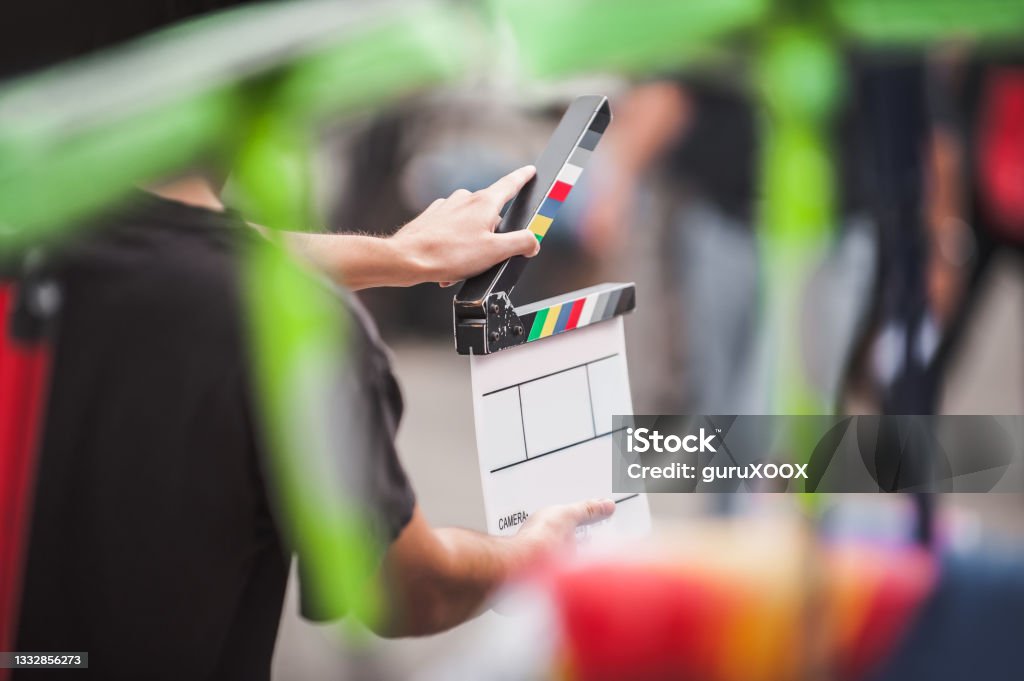 Man holding a clapperboard in front of the camera Filming on location. Man holding a clapperboard in front of the camera, the filming process. Scene on location Film Set Stock Photo