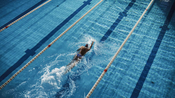 istock Beautiful Female Swimmer Using Front Crawl, Freestyle in Swimming Pool. Professional Athlete Training to Win Championship. Stylish Colors, High Angle Shot with Drammatic Light. 1332857738