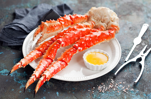 Red king crab legs with butter sauce on a plate, selective focus