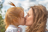 Mom with a little daughter in her arms kissing on the beach