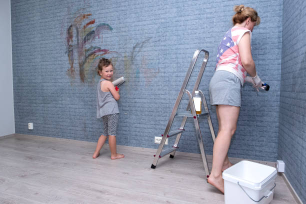 jeune femme caucasienne avec un rouleau de peinture à la main sur un fond mural gris. la femme leva la main et était prête à peindre. espace de copie. - paint roller copy space action adult photos et images de collection