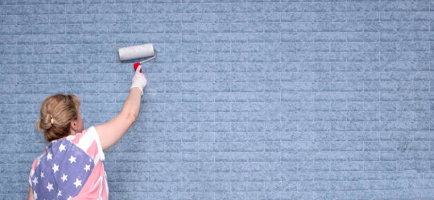 jeune femme caucasienne avec un rouleau de peinture dans les mains. une femme applique un dissolvant de papier peint sur le mur. - paint roller copy space action adult photos et images de collection