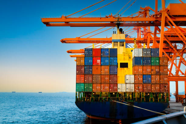 istock Container terminal, container ship discharge cargo at port. Quay crane lift off container box load onto truck. Container port logistics operation. 1332868792