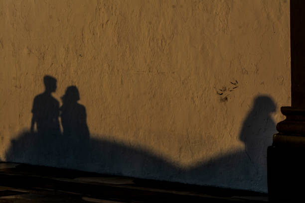 istock Shadow of people projected on the wall in the sunset light. 1332871575